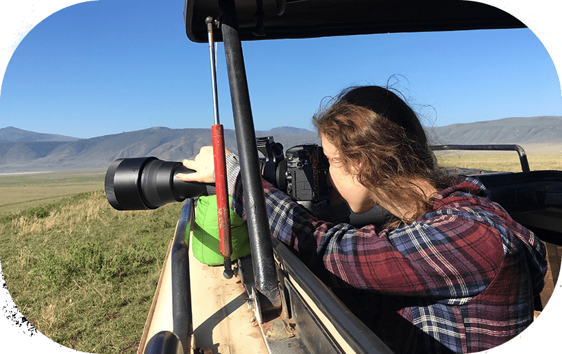 Lady taking photos inside a safari jeep with a professional camera during a photography safari in Tanzania.