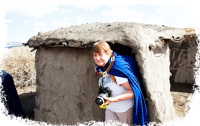 Tourist emerging from a traditional Maasai hut during a walking safari in Tanzania