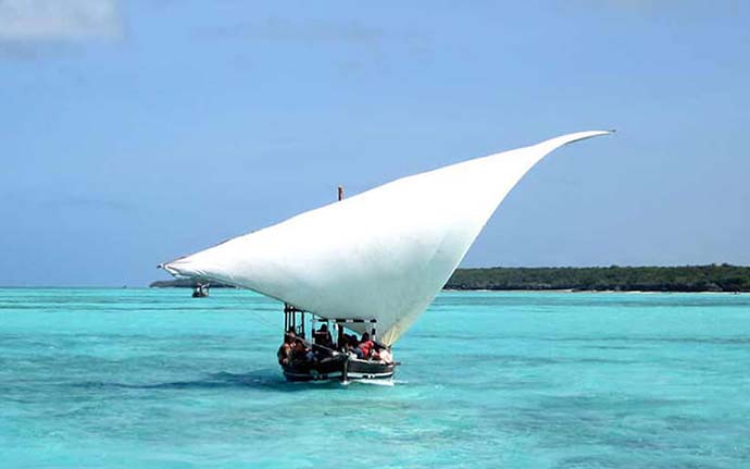 Traditional dhow sailing on the clear blue waters of Zanzibar during sunset.